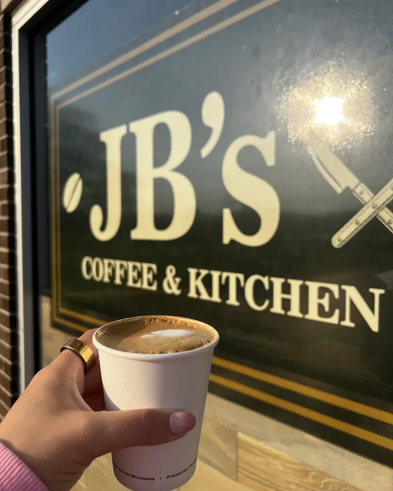 A latte held up at the JB’s Coffee & Kitchen front window